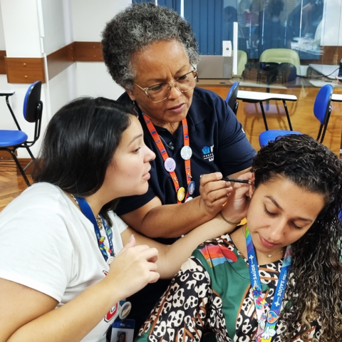 duas mulheres realizando a aplicação de sementes de mostarda na paciente modelo