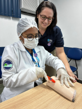 Enfermeira professora apoiando o processo de aprendizadem durante a atividade de simulação realística da participante do curso.